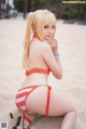 A woman in a red and white bikini sitting on a beach.