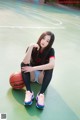 A woman sitting on a basketball court with a ball.