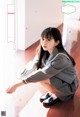 A woman in a school uniform sitting on the floor.