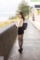 A woman in a black skirt and white top is standing on a bridge.